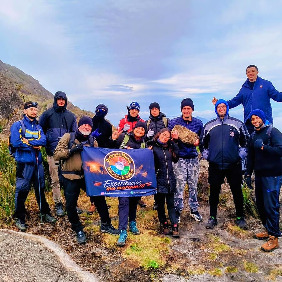 Turma agasalhada posando com a faixa da Desbrava Mundi